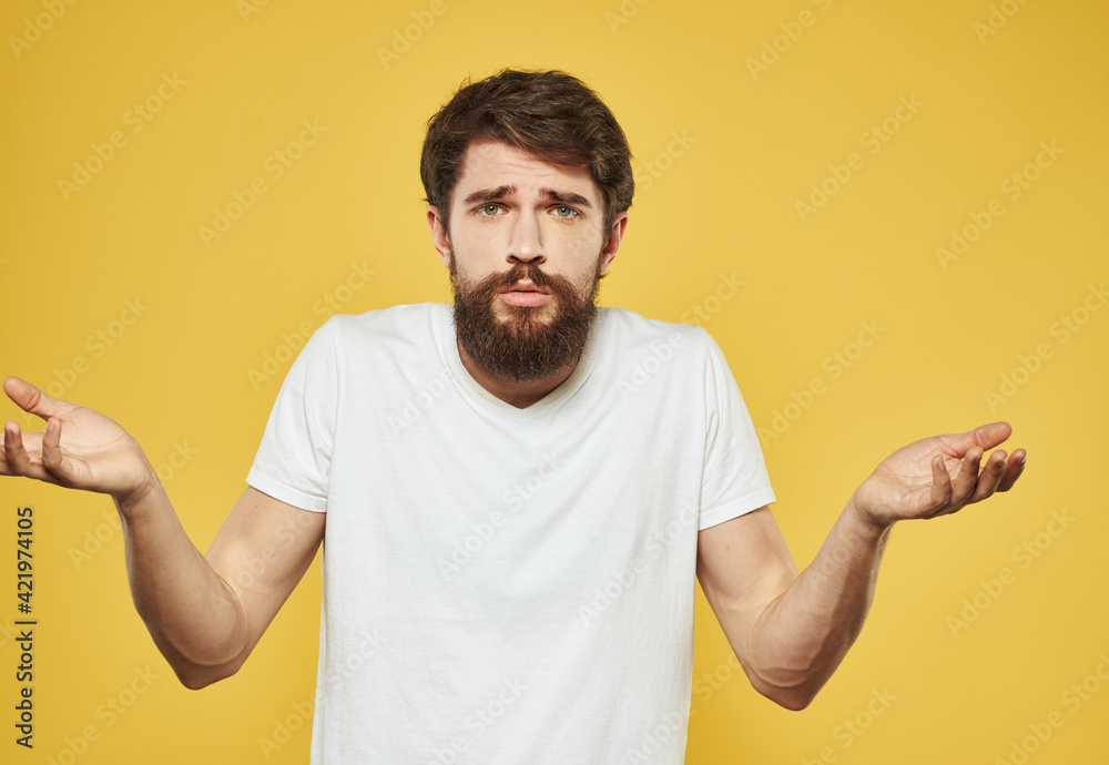 Puzzled look man gesturing with his hands on a yellow background cropped view of the model Puzzled look man gesturing with his hands on a yellow background cropped view of the model