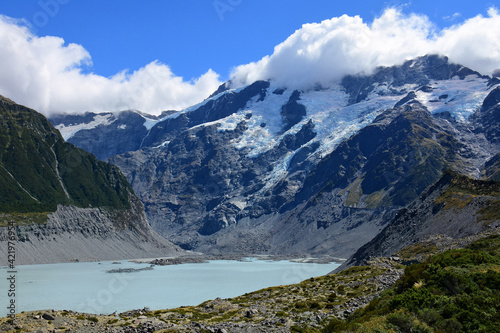 spectacular view of rugged mountain peaks and a glacial lake along the hooker valley track on a sunny summer day, near mount cook village, on the south island of new zealand