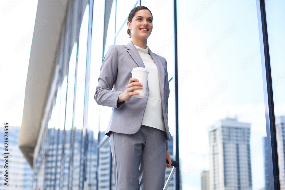 Fototapeta premium Portrait of successful business woman traveling with case at airport. Beautiful stylish female travel with luggage.