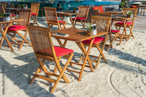 Wooden table and chairs in empty beach cafe next to sea water. Close up  Thailand