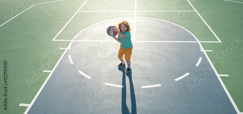 Happy little boy kid playing basketball on playground. Child sportsman.