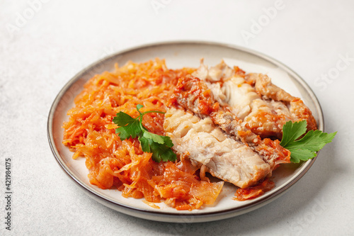 Fish pollock fillet with garnish stewed cabbage in a plate on the table. Healthy diet photo
