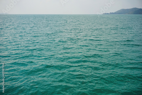 The surface of the water is calm in the middle of the sea. The sea is wide open, the horizon and the blue green turquoise water surface. Photos from a boat in the middle of the ocean.  photo