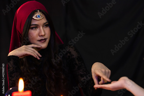 Asian fortune teller pointing at hand of customer