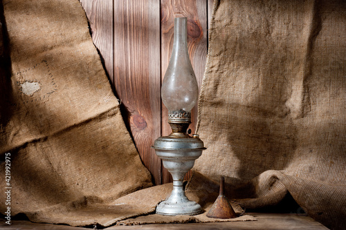 Принти на полотні A vintage kerosene lamp covered in dust and soot, shot against a background of wood panels and burlap