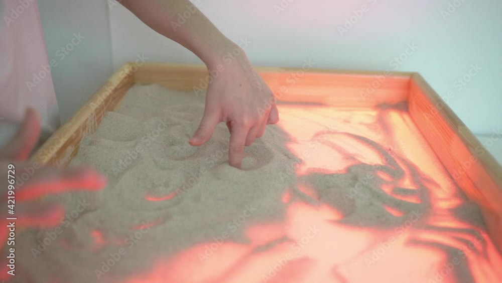 Close-up boy plays with car on sand at the white light table at the white room Close-up boy plays with car on sand at the white light table at the white room