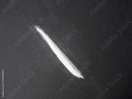a white line of powder on a black background. The concept of prohibited substances, drugs, deadly substances, addiction