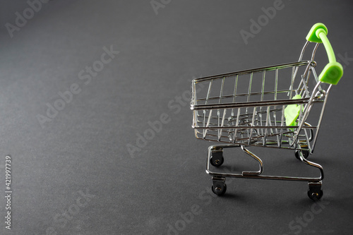 Close-up of green shopping carts on a black background. Sales concept. Cart, products, copy space. Side view