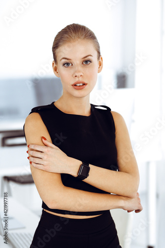 Young blond businesswoman is standing straight in modern office. Business people concept. Black dress do suits to her much at this portrait Free Download Young blond businesswoman is standing straight in modern office. Business people concept. Black dress do suits to her much at this portrait - GFXLoad