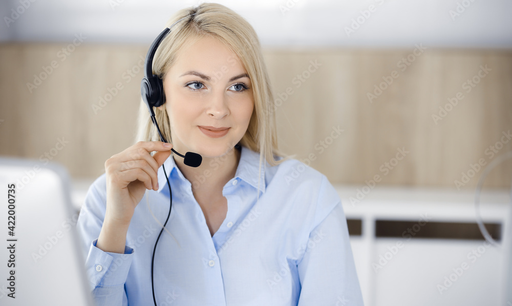 Blonde business woman sitting and communicated by headset in call center office. Concept of telesales business or home office occupation Blonde business woman sitting and communicated by headset in call center office. Concept of telesales business or home office occupation