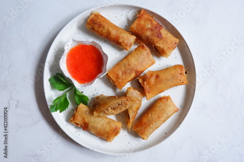 a plate of fried spring rolls served with sauce