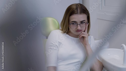 Adult female patient sits on dental chair with toothache and waits for theatment photo