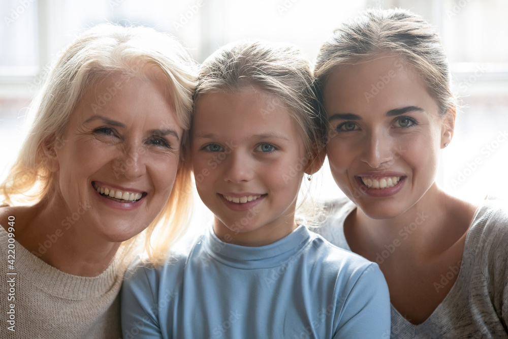Close up headshot portrait of happy Caucasian three generations of women show family unity pose at home together. Profile picture of smiling little girl child with young mother and senior grandmother. Close up headshot portrait of happy Caucasian three generations of women show family unity pose at home together. Profile picture of smiling little girl child with young mother and senior grandmother.