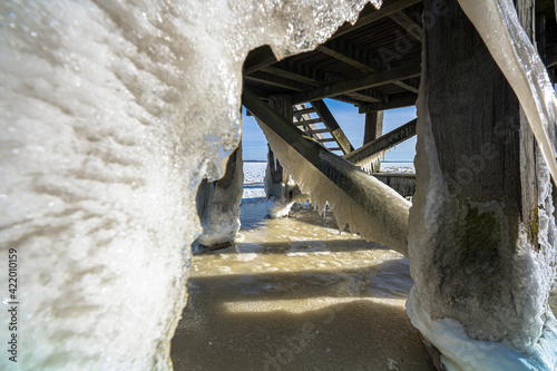 Mooring post with wooden pier with ice sculptures in winter landscape at Dutch lake photo