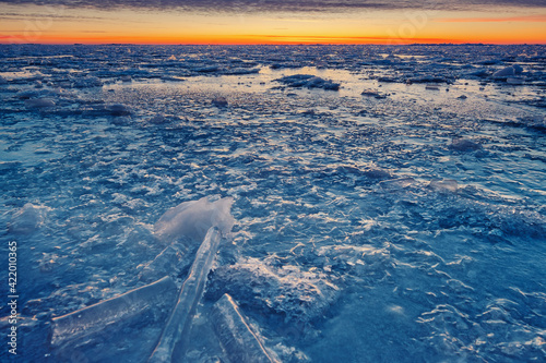 Icy frozen shore of the lake in sunset time.