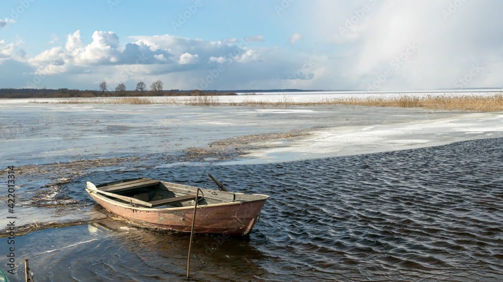 winter landscape with lake, old wooden boat in the lake, expressive clouds, Lake Burtnieki winter landscape with lake, old wooden boat in the lake, expressive clouds, Lake Burtnieki