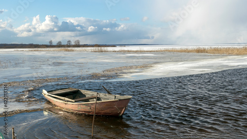 Tableau sur toile winter landscape with lake, old wooden boat in the lake, expressive clouds, Lake