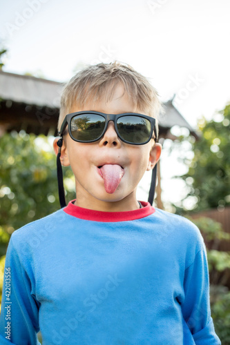 Portrait of funny cute boy wearing glasses and showing tongue. funny emotional boy