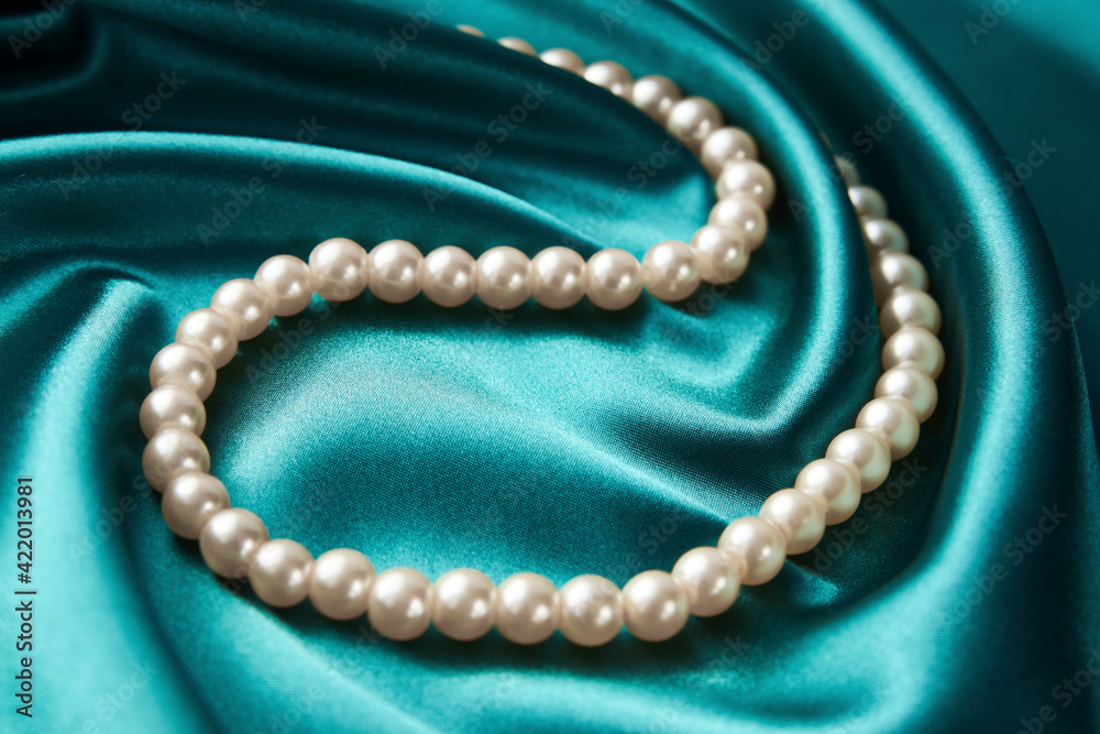 Pearl necklace on green background, close-up Pearl necklace on green background, close-up