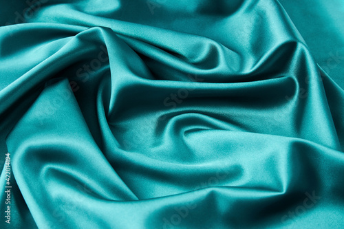 Green silk fabric background, top view, close-up