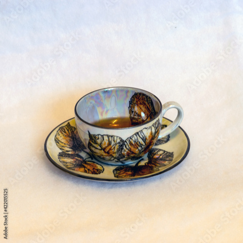 decorated tea mug with saucer on a white background