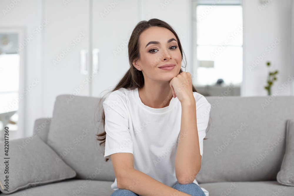 Smiling happy woman sitting on the couch at home while online communication look at camera, Smiling happy woman sitting on the couch at home while online communication look at camera,