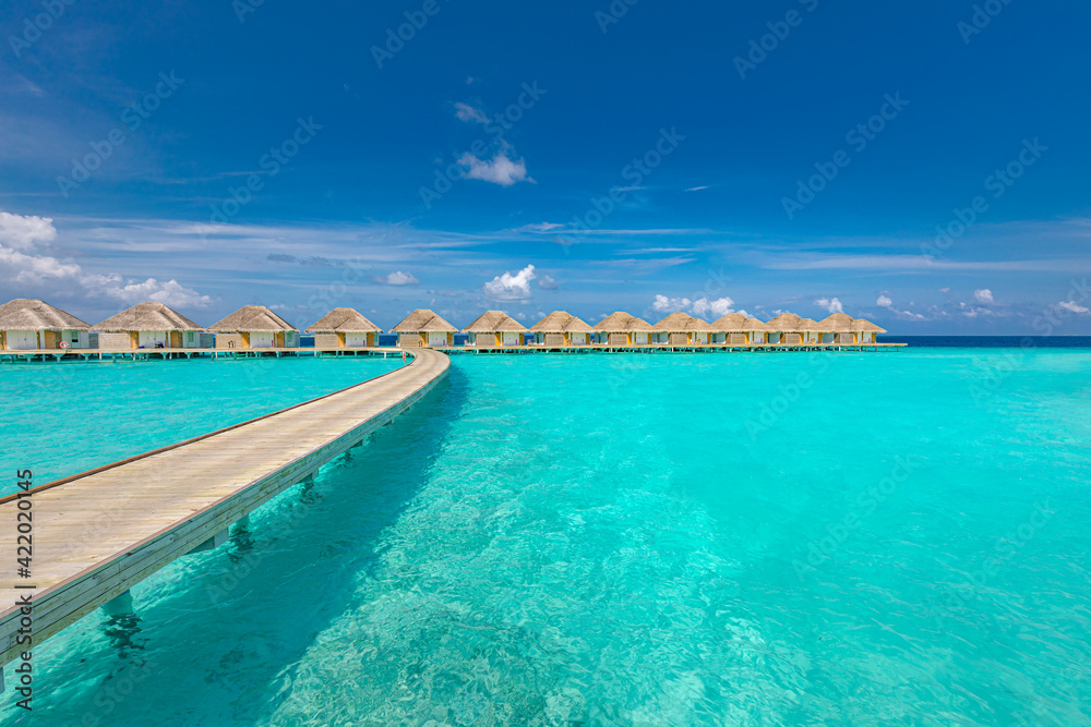 Ocean lagoon bay view, blue sky and clouds with wooden jetty and over water bungalows, villas, endless horizon. Meditation relaxation tropical background, sea ocean water. Skyscape seascape background