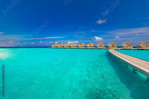 Fototapeta Naklejka Na Ścianę i Meble -  Ocean lagoon bay view, blue sky and clouds with wooden jetty and over water bungalows, villas, endless horizon. Meditation relaxation tropical background, sea ocean water. Skyscape seascape background
