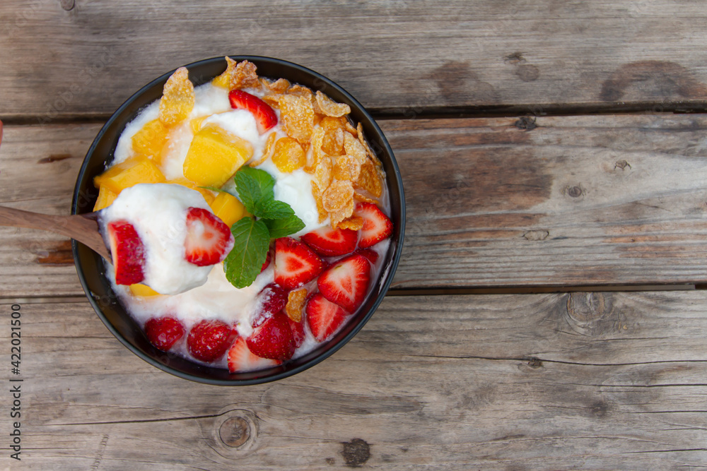 yogurt mixed fruit Strawberries mango conflex mint on wooden table top view yogurt mixed fruit Strawberries mango conflex mint on wooden table top view