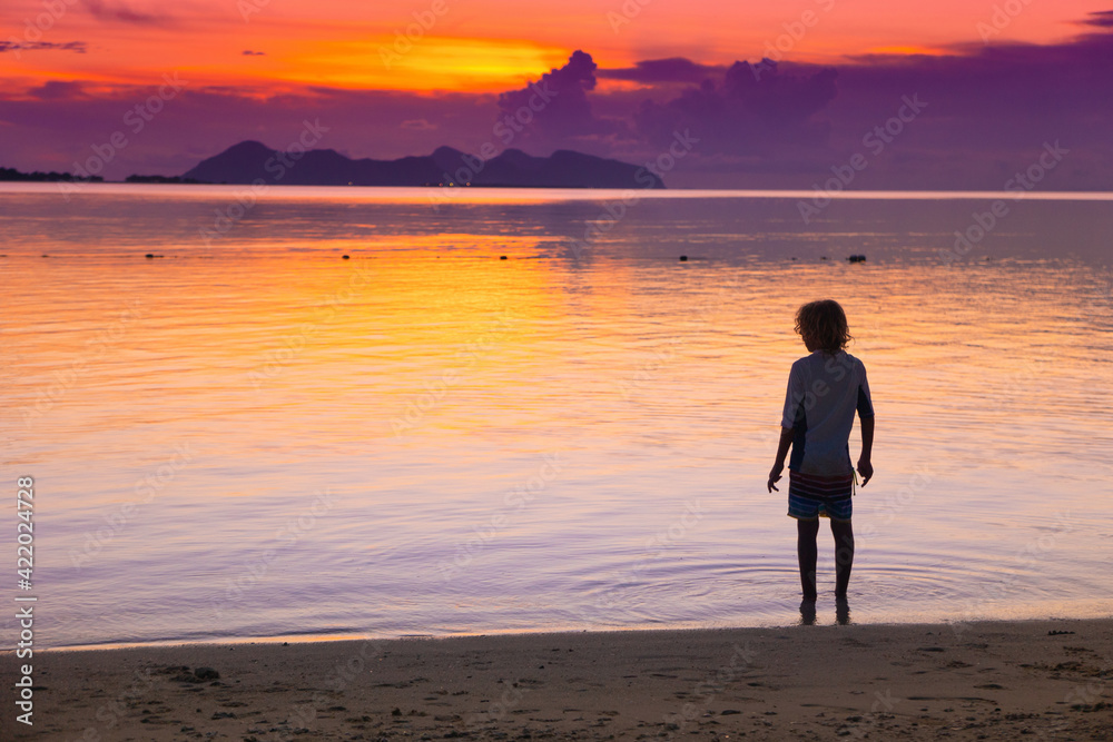 Child playing on ocean beach. Kid at sunset sea.