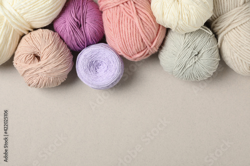 Soft woolen yarns on light background, flat lay. Space for text