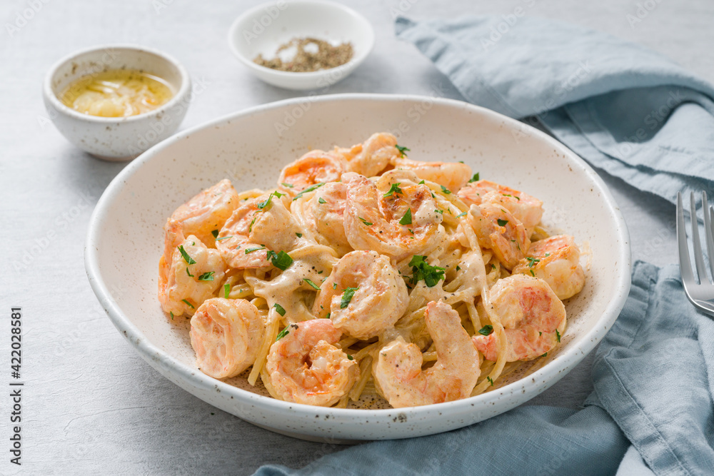Pasta spaghetti with grilled shrimps bechamel sauce. Spaghetti with seafood rich cream. Cooking mediterranean food with savory prawns, macro side view, blue table, italian cuisine Pasta spaghetti with grilled shrimps bechamel sauce. Spaghetti with seafood rich cream. Cooking mediterranean food with savory prawns, macro side view, blue table, italian cuisine