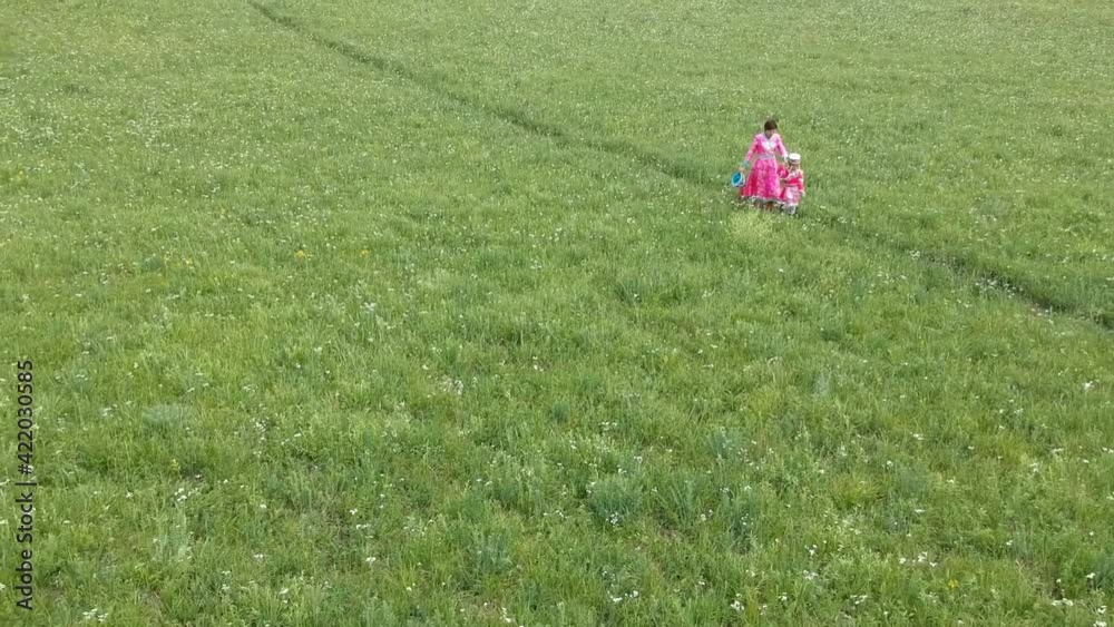 Aerial photo of mother and daughter in Mongolian costume walking on the vast grassland Aerial photo of mother and daughter in Mongolian costume walking on the vast grassland