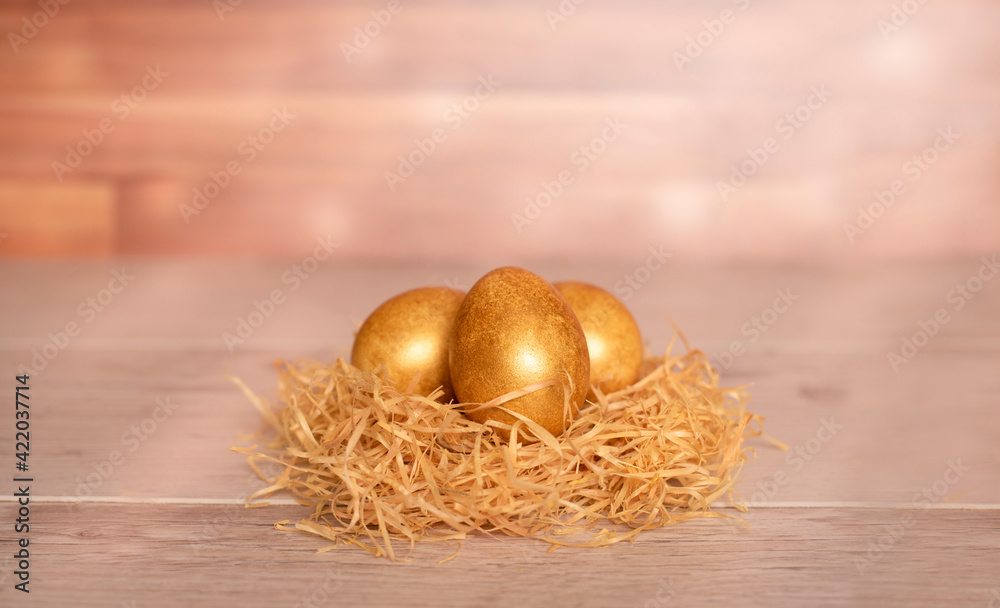 three golden easter eggs in a nest on a wooden table three golden easter eggs in a nest on a wooden table