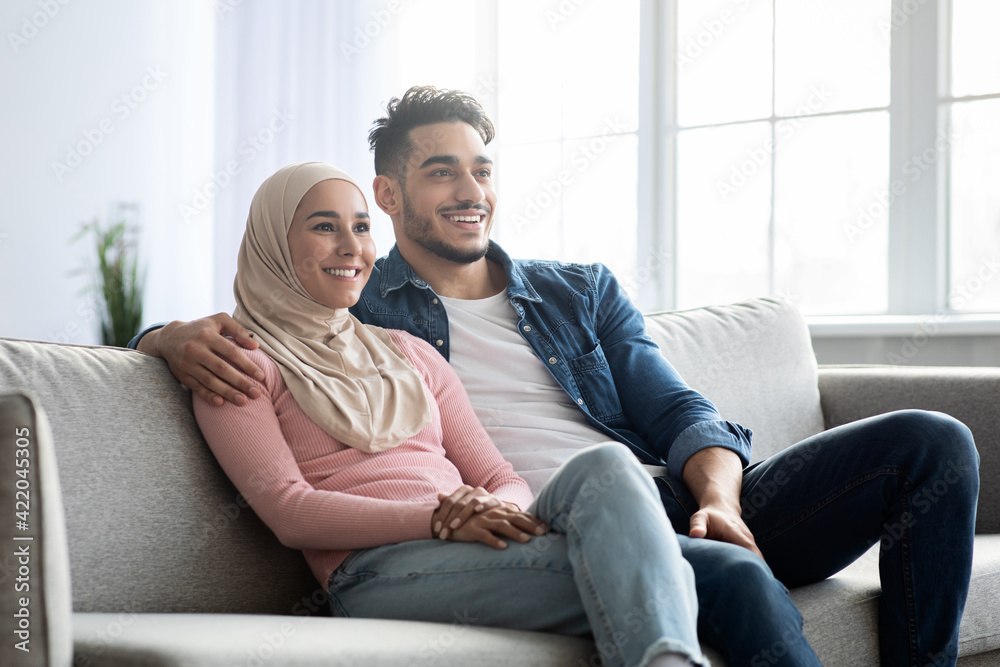 Cheerful muslim family sitting on sofa at home