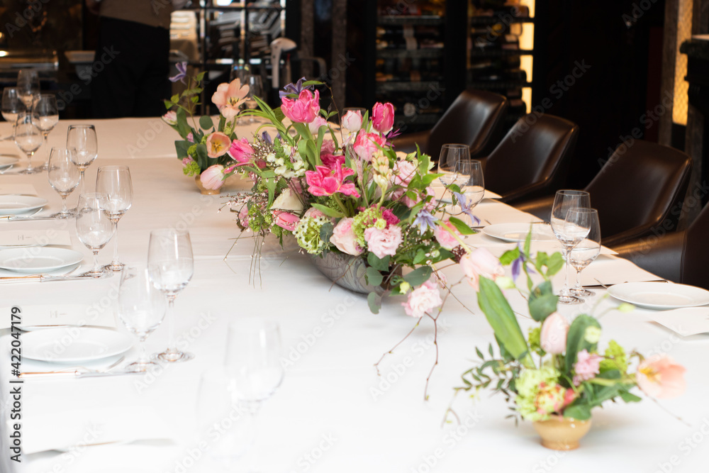 beautiful composition of pink flowers with greenery, on a table with a white tablecloth, indoors, in a hotel, in the afternoon. Florist work, wedding decor, holidays. Profitable business, table decora