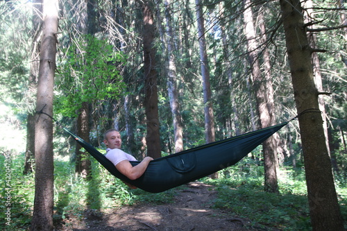 A boy is lying on his hammock in the woods