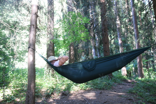 A boy is lying on his hammock in the woods