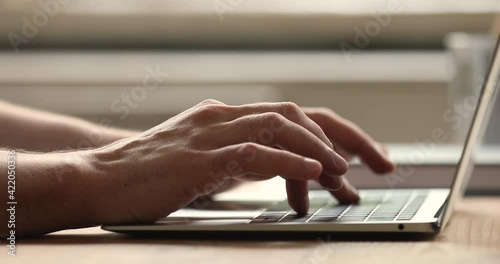 Close up male hands typing message on laptop. Businessman sit at desk texting e-mail, correspond to client remotely, writes text on portable wireless pc keyboard, modern electronic tech usage concept