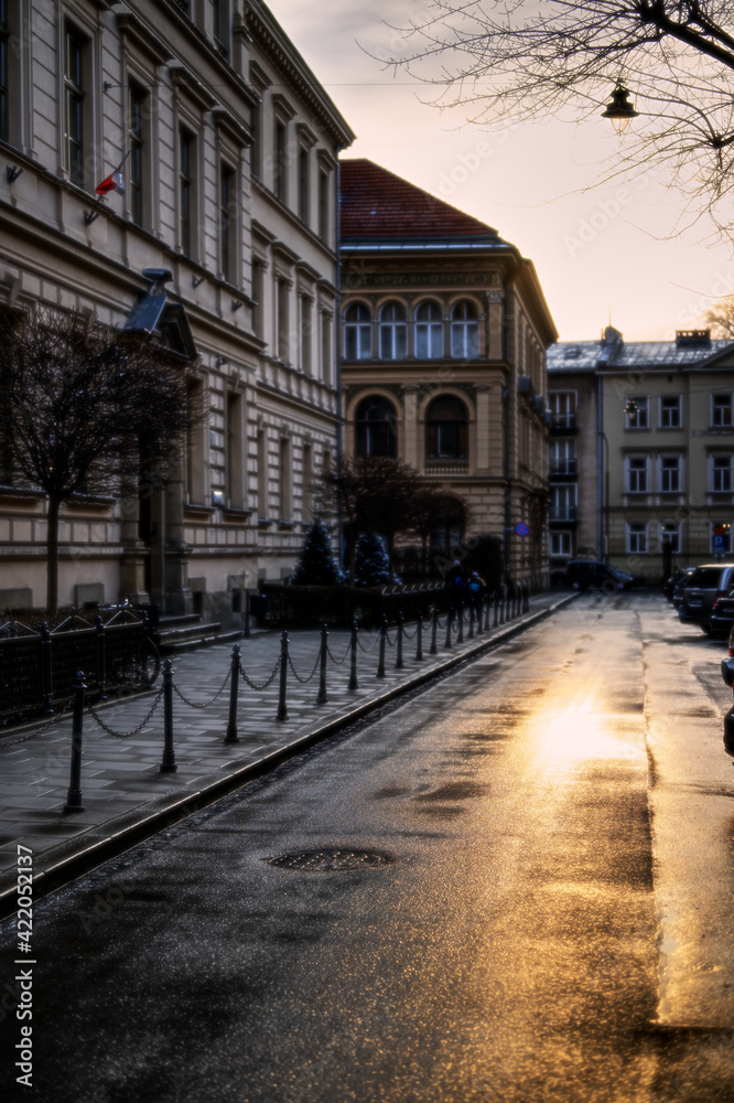 Shot of sunset over Studencka Street in Cracow. Beautiful golden glow reflected on wet road.
