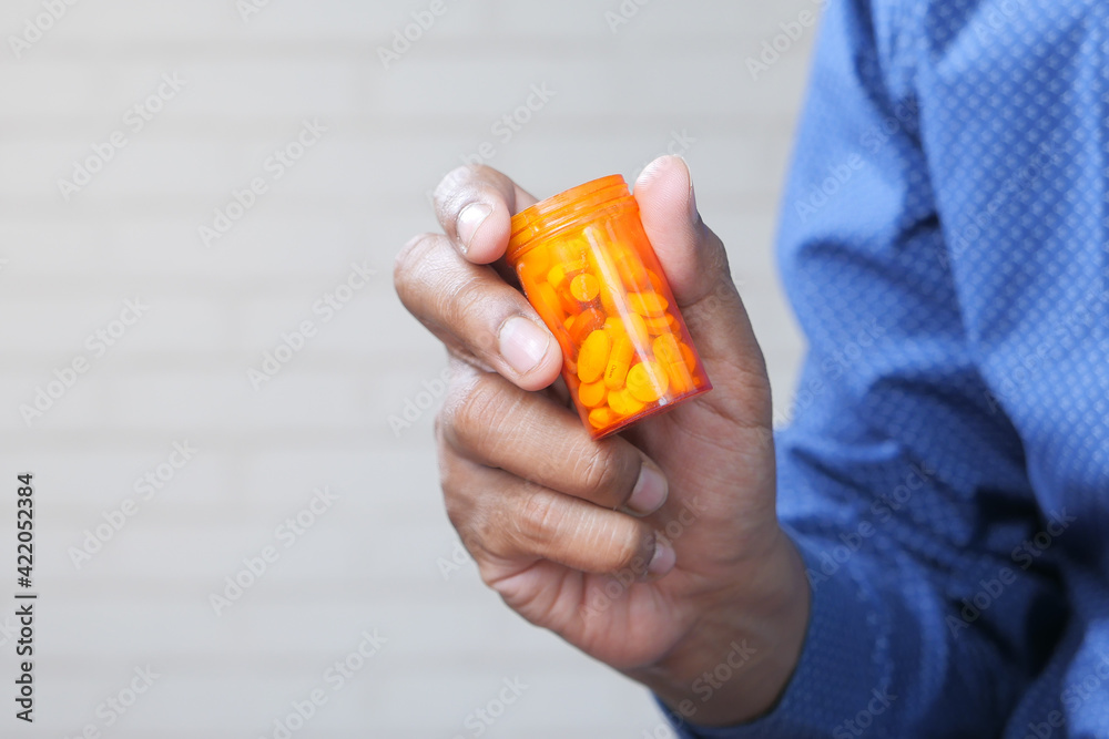 person hand holding pill container person hand holding pill container