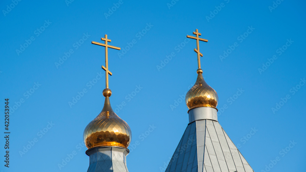 Golden domes with Christian crosses on a blue sky background. The concept of the Church