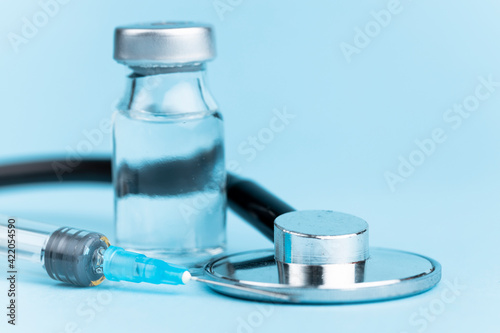 Vaccine vial with syringe and stethoscope on a blue background