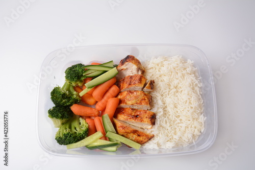 Healthy balanced lunch boxes. Grilled chicken, carrots, cucumbers, broccoli, and white rice. Lunch boxes with food ready to go for work or school. Office food lunch concept