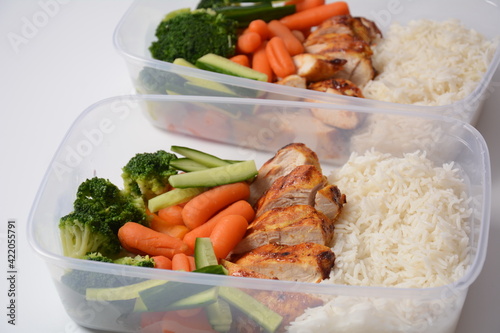 Healthy balanced lunch boxes. Grilled chicken, carrots, cucumbers, broccoli, and white rice. Lunch boxes with food ready to go for work or school. Office food lunch concept