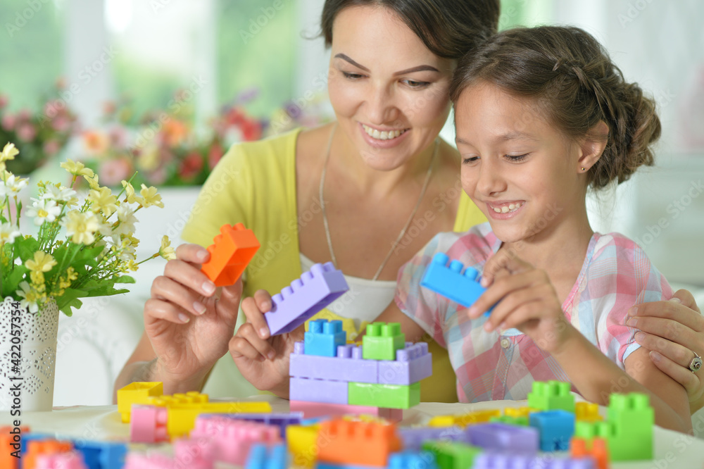 little daughter and mother playing with colorful plastic blocks at home little daughter and mother playing with colorful plastic blocks at home