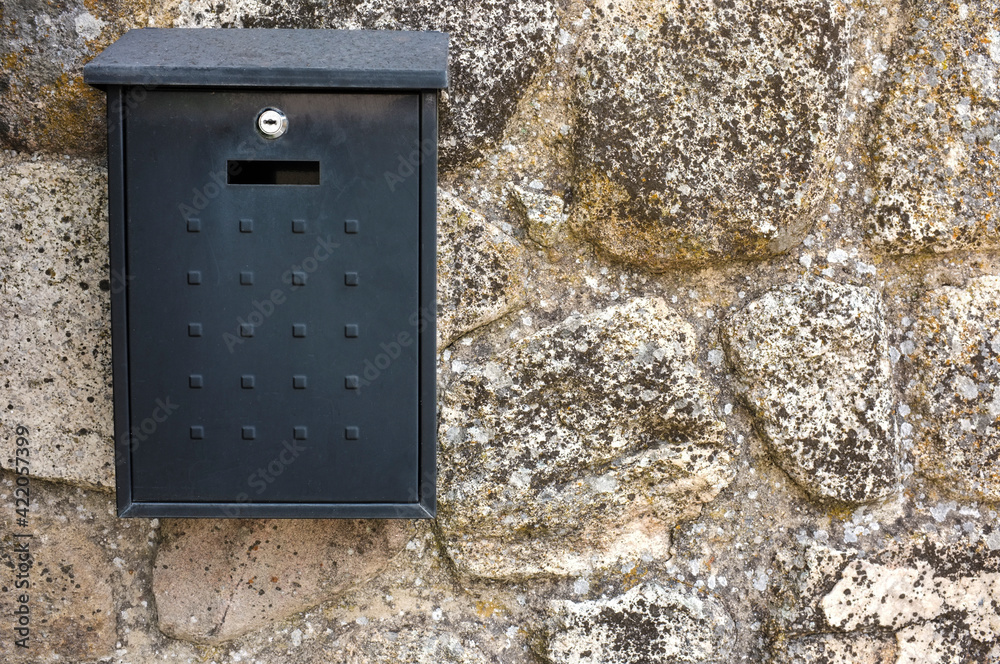 Black metal mailbox attached on cottage wall house