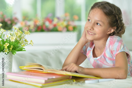 little cute girl reading book at the table at home