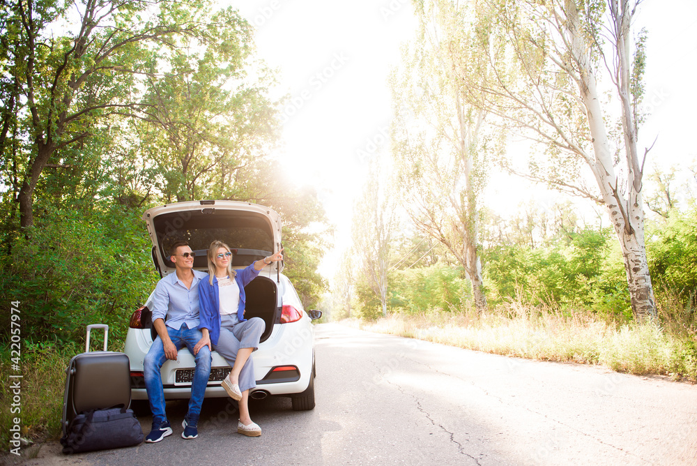Young couple sits in the trunk of a car and chooses where to travel. Young couple sits in the trunk of a car and chooses where to travel.