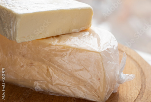 farm, dairy products, a piece of butter and cheese, wrapped in plastic wrap, lie on a wooden board, on a light background. Food, Vegan Oil, Healthy Eating, Daily Diet, Dairy Benefits